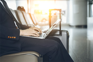 Business man on laptop seated at a gate in the airport.